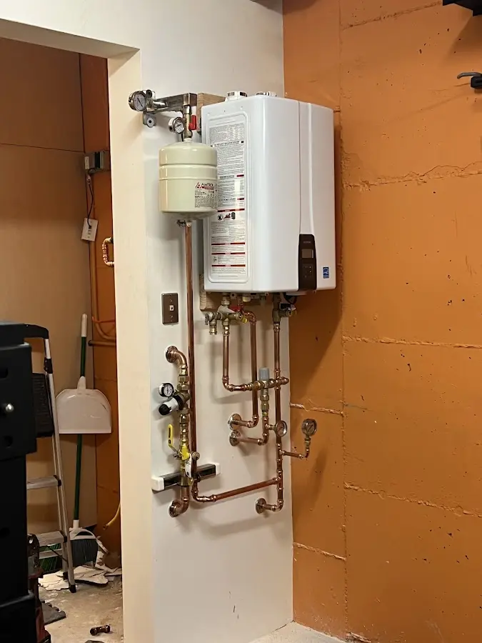 Plumbing technician inspecting water heater connections in Gray